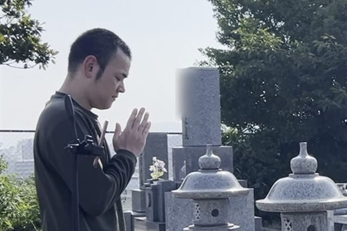 普段着でお墓の前に立ち、手を合わせる