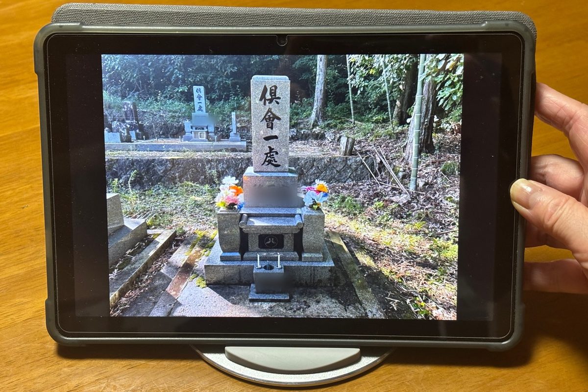 お墓の前で、タブレットの画面ごしにビデオ通話でお参りする様子