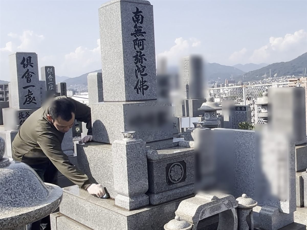 墓石のすみずみまで、手で丁寧に拭き上げる様子